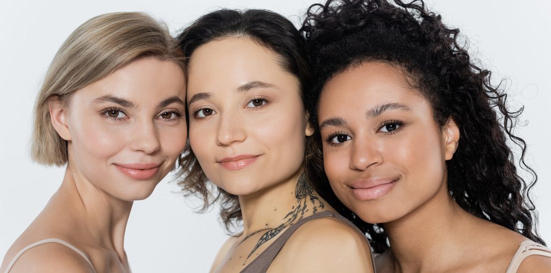 Young interracial women looking at camera isolated on grey Skincare solution